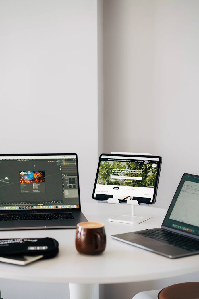 Efficient remote workspace featuring dual laptops, tablet, and coffee mug on a desk.